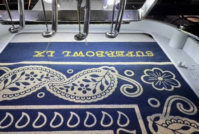 Custom lettering being embroidered onto a bandana on site